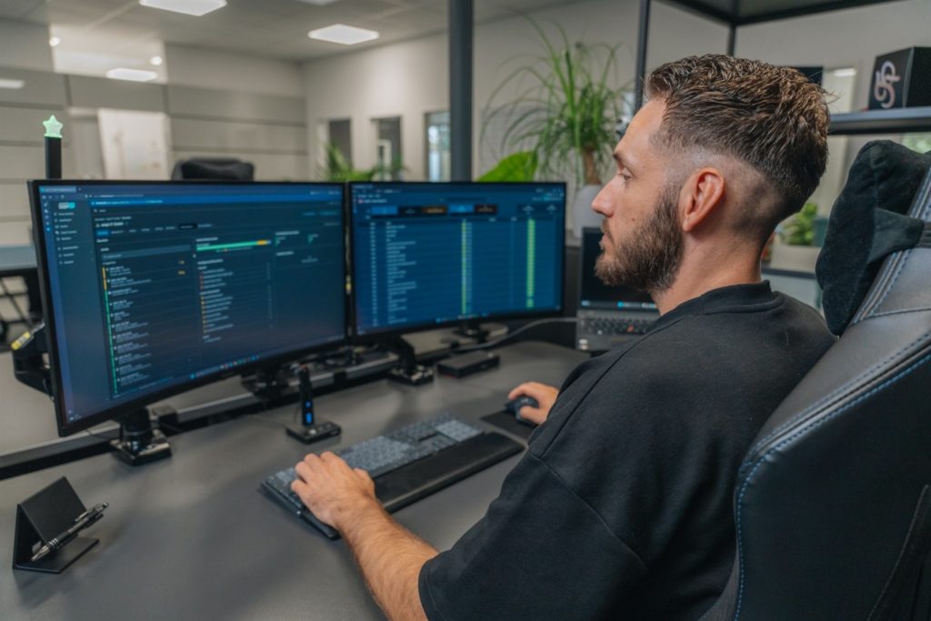 Kollege arbeitet an zwei gebogenen Monitoren im Büro