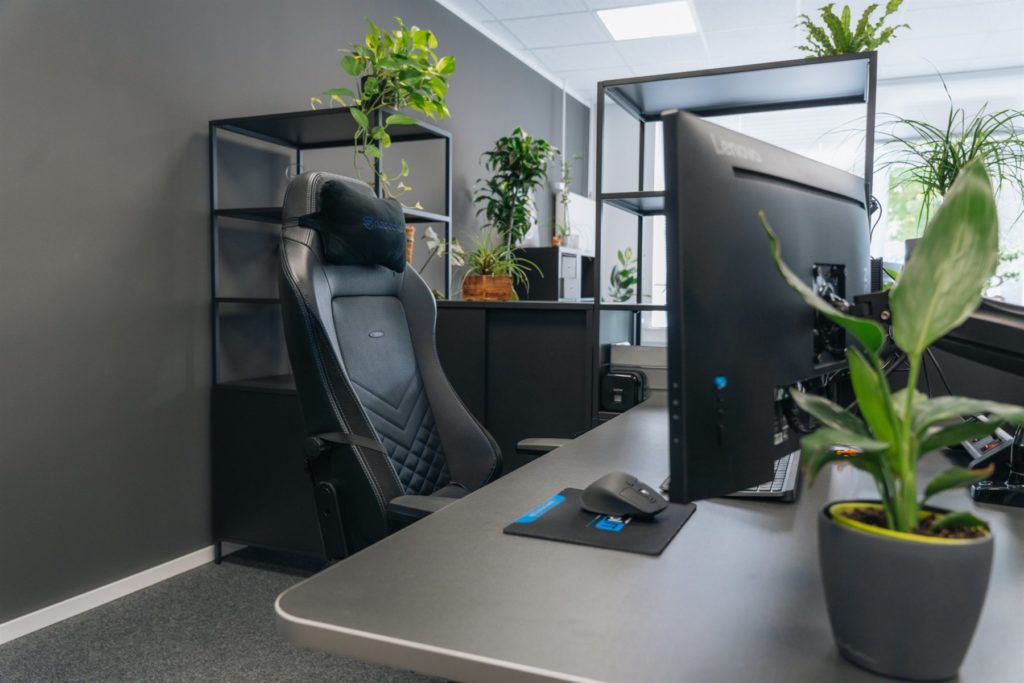 Arbeitsplatz mit Gaming-Stuhl, Monitor und vielen Pflanzen