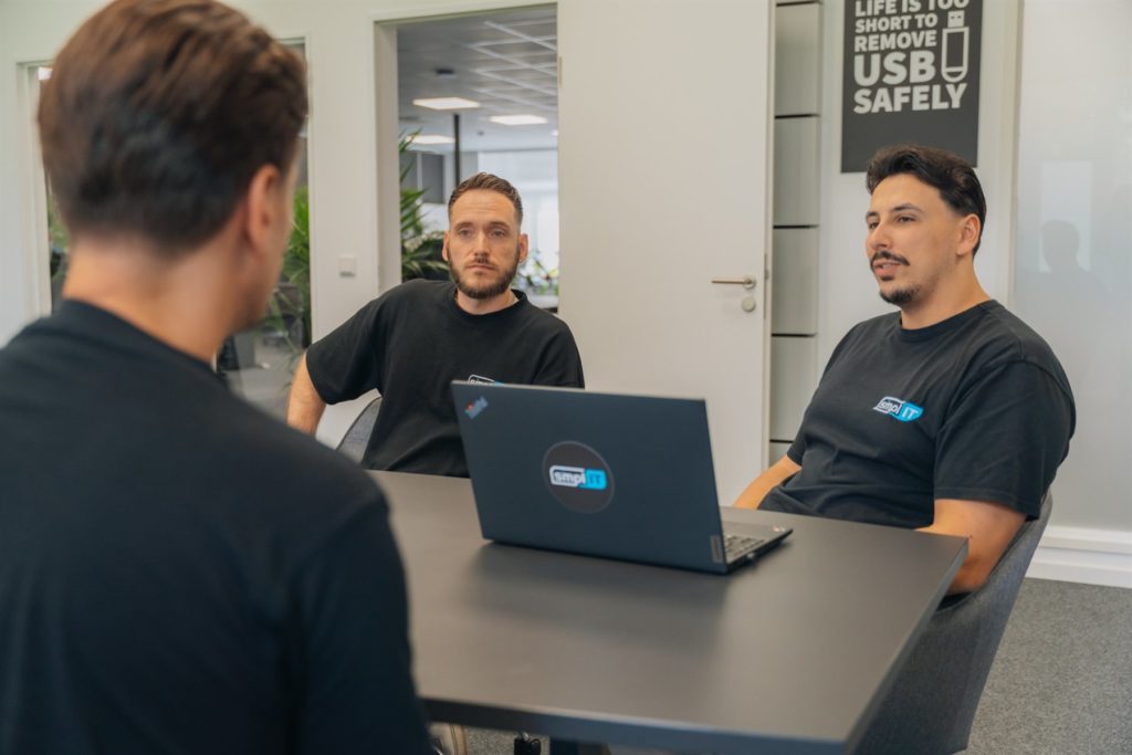 Zwei Kollegen im Gespräch am Besprechungstisch mit Laptop