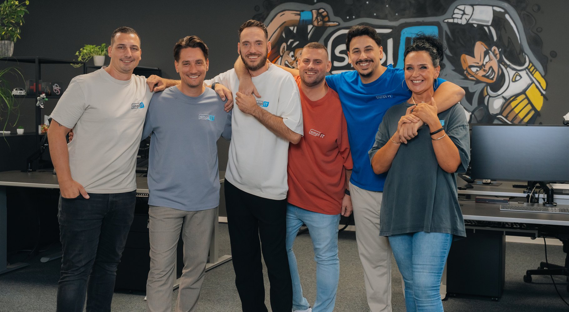 Das smpl-IT Team im Büro in Leverkusen: sechs Kolleginnen und Kollegen lachen gemeinsam in die Kamera